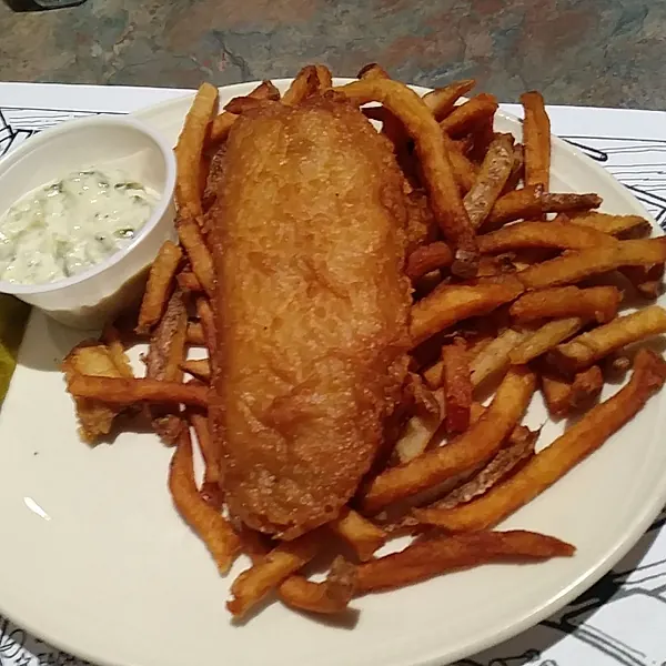 Fish and chips with tartar sauce and a pickle